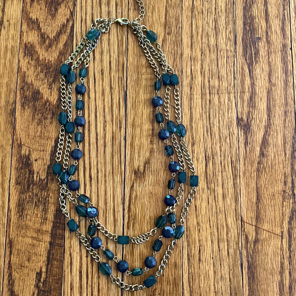 Gold necklace with emerald green beads. 3 strand and tiered.